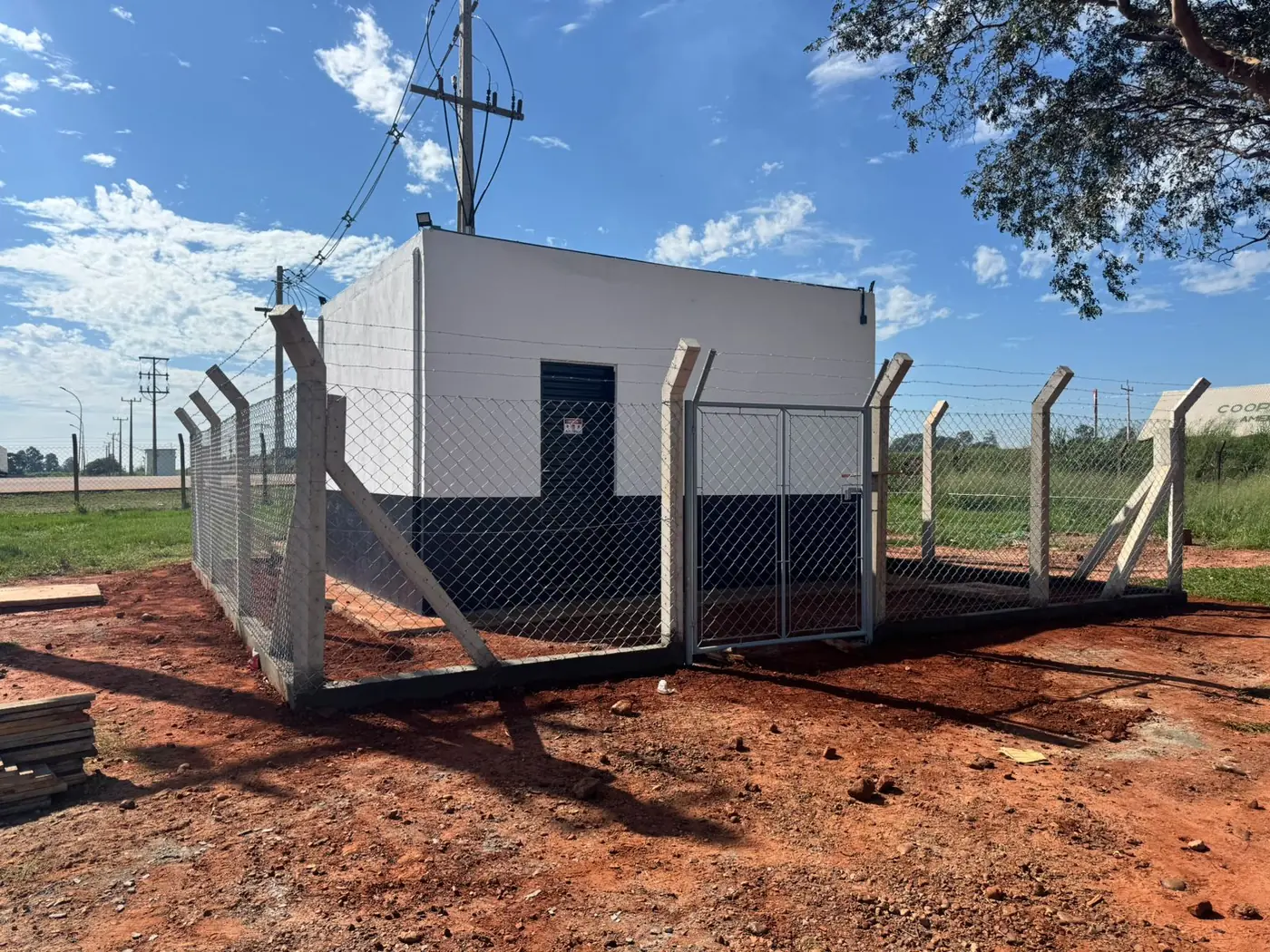 Mourões de concreto e alambrado cercando área industrial